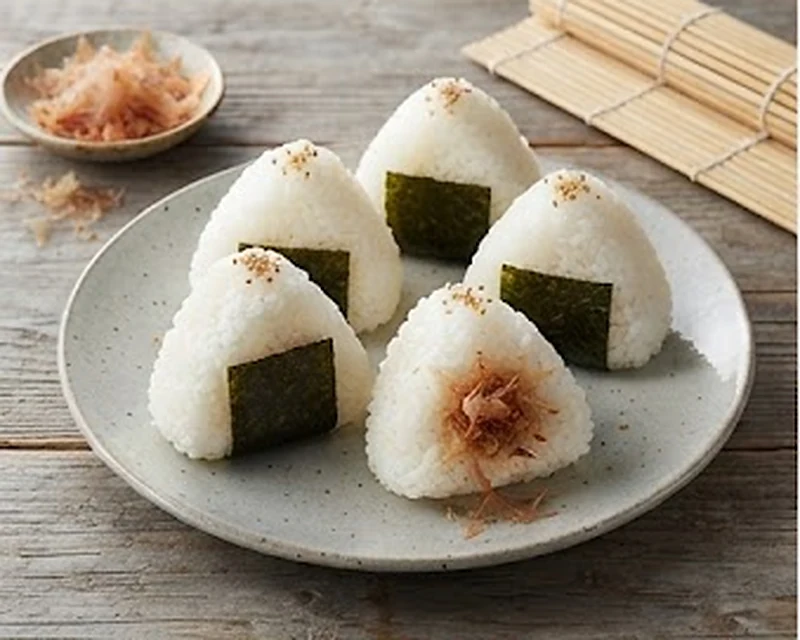 Deux onigiri triangulaires frais enveloppés d'une bande d'algue nori sur une planche en bois